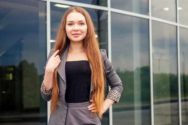 Confianza empresaria profesional femenina en ropa formal posando en el modelo de moda de fondo de rascacielos de oficina de centro de negocios de la calle