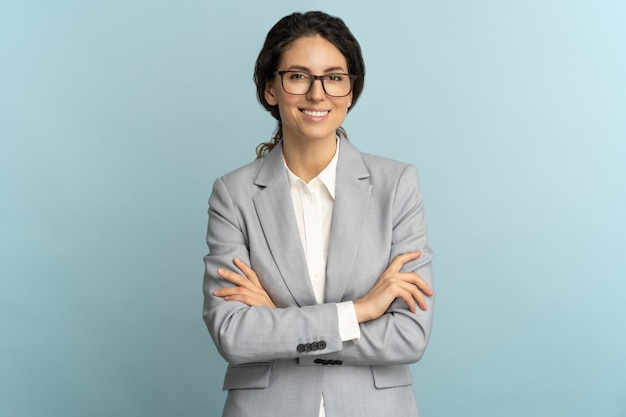 Confianza empresaria, sonriendo, mirando a la cámara de pie con los brazos cruzados aislados en el estudio.