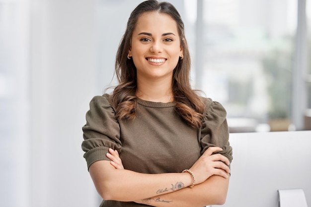 La confianza juega un papel muy importante en el éxito. Retrato recortado de una atractiva joven empresaria parada con los brazos cruzados en la oficina.