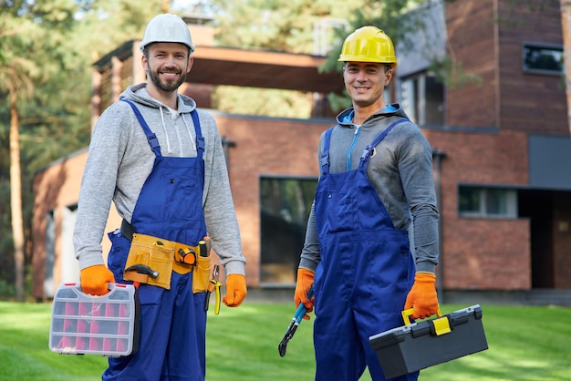 Confie em nós dois jovens engenheiros positivos e bonitos em capacetes, sorrindo para a câmera