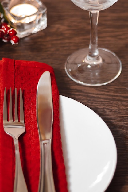 Configuração da mesa de Natal Prato e talheres em guardanapo vermelho Velas queimando na mesa na véspera de Natal Preparando-se para um jantar festivo Foto vertical