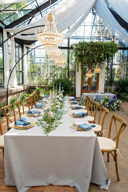 Configuração de mesa de banquete de casamento com guardanapos azuis, talheres de ouro, cristal, flores frescas e velas. Decorações de casamento. Foco seletivo suave.