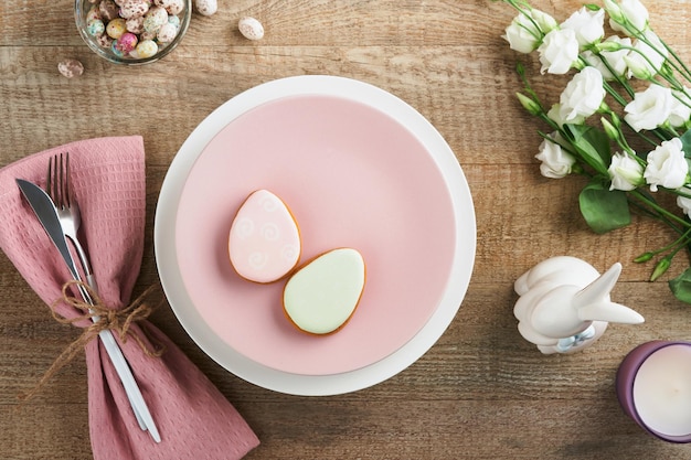 Configuração de mesa de brunch de Páscoa Conceito de feriado de Páscoa de primavera com prato rosa branco e guardanapo com símbolos decorativos ovos de coelho de férias e buquê de flores em fundo de madeira velho Vista superior