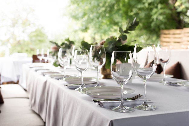 Configuração de mesa de casamento decorada com flores frescas em um vaso de latão. Floricultura de casamento. Mesa de banquete para os hóspedes ao ar livre com vista para a natureza verde. Bouquet com rosas, eustoma e folhas de eucalipto