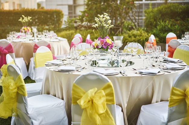 Configuração de mesa de jantar de recepção de casamento com decoração de flores e cadeiras de cobertura brancas