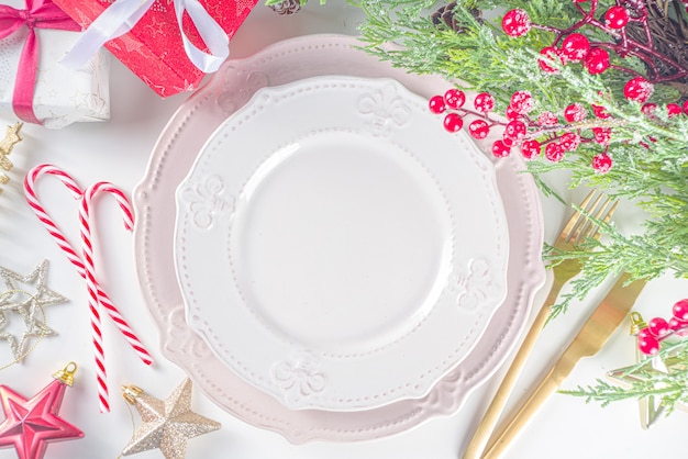 Configuração de mesa de Natal com pratos vazios, caixa de presente e decoração de Natal. Vista superior plana com espaço de cópia, fundo branco