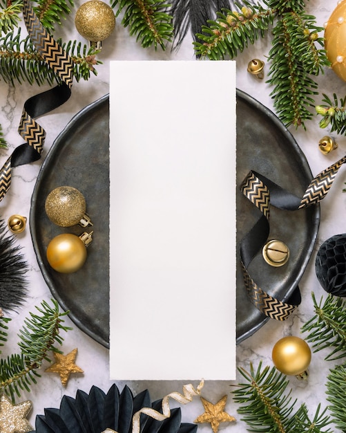 Foto configuração de mesa de natal preta e dourada com ornamentos e galhos de árvores de abeto cartão de menu mockup