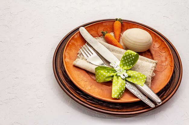 Configuração de mesa de Páscoa em plano de fundo texturizado branco massa de vidraceiro. Modelo de cartão de férias de primavera. Talheres, guardanapo vintage, ovo, cenoura, coelho