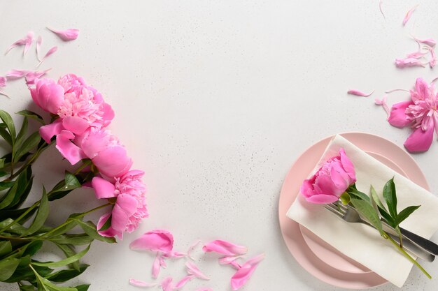 Configuração de mesa de primavera com flores de peônia rosa sobre uma mesa branca. Vista de cima.