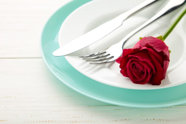 Configuração de mesa de restaurante romântico com rosa vermelha em pratos