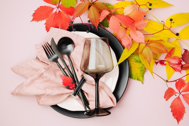 Configuração de mesa festiva com folhas de outono brilhantes em fundo pastel.