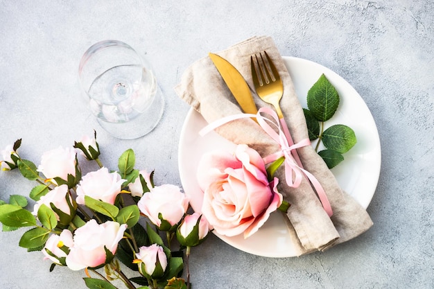 Configuração de mesa festiva com prato branco e flores rosas Decoração de mesa para um aniversário ou casamento Flat lay com espaço de cópia