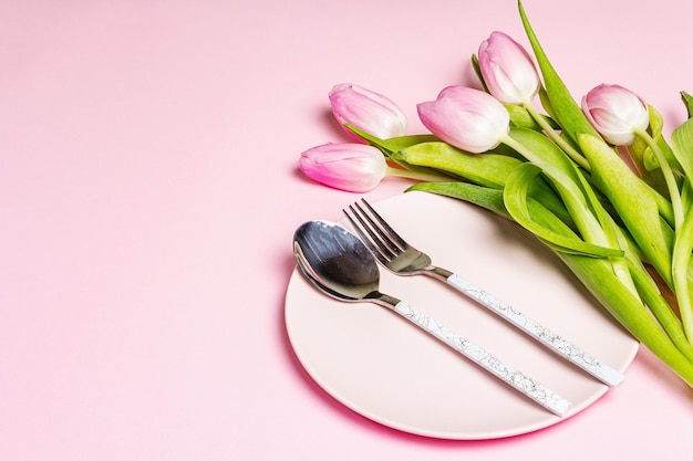 Configuração de mesa rosa criativa festiva com tulipas no fundo rosado suave