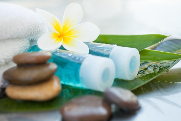 Configuração de spa ou bem-estar com flores tropicais e pequena garrafa com óleo Cuidado corporal e conceito de spa