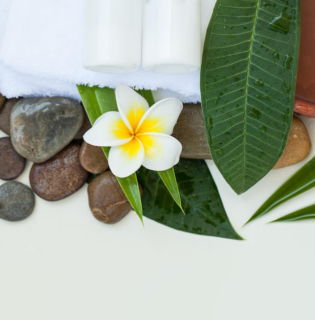 Configuração de spa ou bem-estar com tigela de flores tropicais de toalha de água e tubo de creme