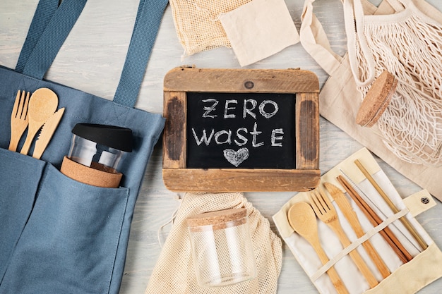 Foto configuração plana do kit zero waste. conjunto de talheres de bambu ecológicos, saco de malha de algodão, copo de café reutilizável, escovas e garrafa de água. estilo de vida sustentável, ético e sem plástico. vista do topo