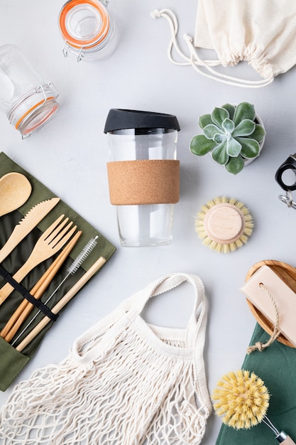 Foto configuração plana do kit zero waste. conjunto de talheres de bambu ecológicos, saco de malha de algodão, copo de café reutilizável, escovas, sabonete e garrafa de água. estilo de vida sustentável, ético e sem plástico