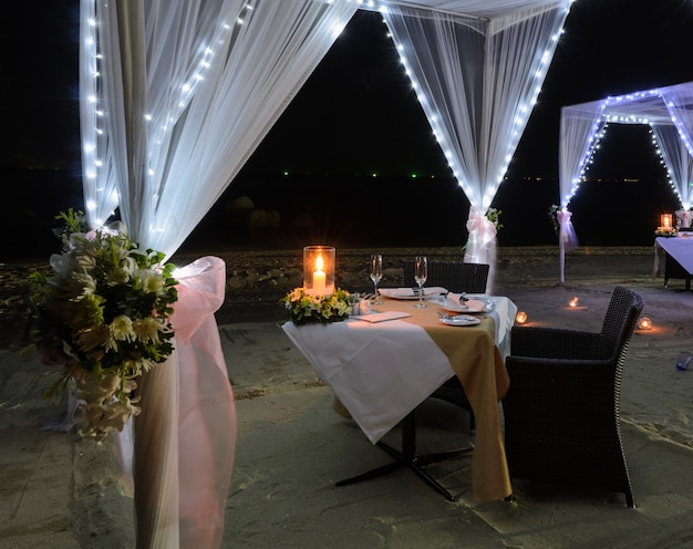 Configuración de cena romántica en la playa por la noche