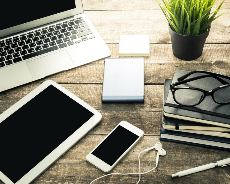Foto configuración del espacio de trabajo con portátil, teléfono inteligente, tableta y estacionario en una mesa de madera en un entorno acogedor