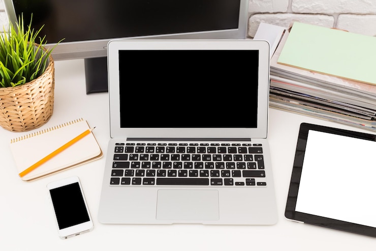 Foto configuración del espacio de trabajo con una tableta portátil, un teléfono inteligente y artículos de papelería en un escritorio con una planta y revistas
