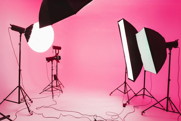 Configuración de estudio con equipos de iluminación en un telón de fondo rosado para sesiones de fotos y videos creativos