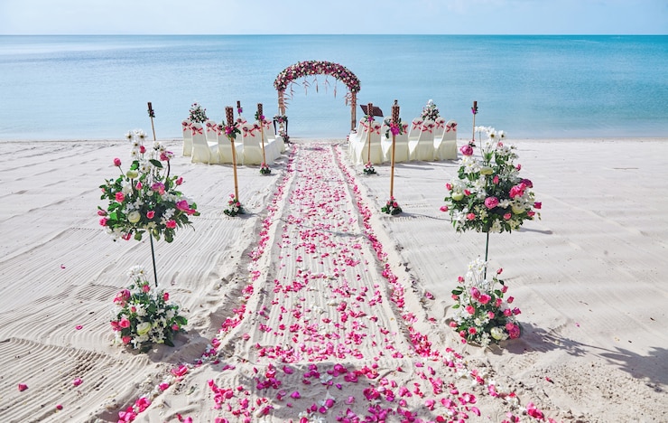Configuración de lugar de boda de playa decorar con ramo de pétalos de rosas rojas y rosas