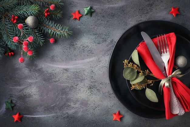 Configuración de mesa navideña con platos oscuros decorados y vajilla en la oscuridad con espacio de copia