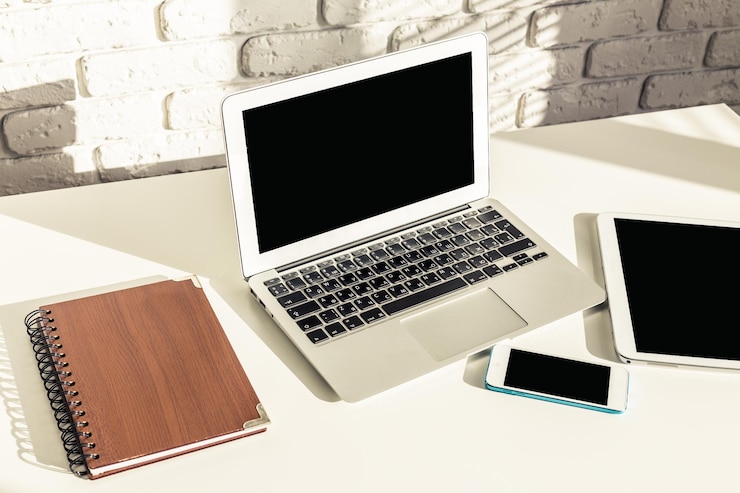 Foto configuración moderna del espacio de trabajo con un ordenador portátil, una tableta, un teléfono inteligente y un portátil en un escritorio limpio con un diseño minimalista