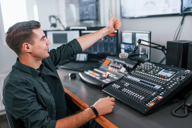 Configurando o equipamento Jovem está dentro de casa no estúdio de rádio está ocupado por transmissão