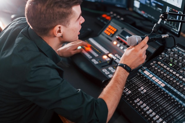 Foto configurando o equipamento jovem está dentro de casa no estúdio de rádio está ocupado por transmissão