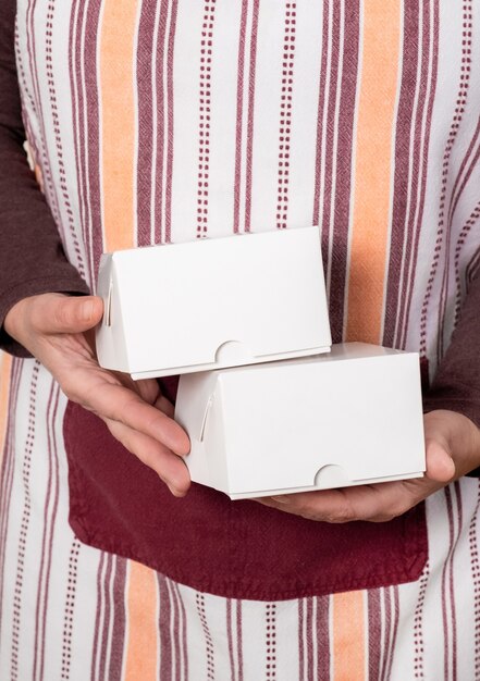 Confitero o entregar sosteniendo dos cajas de papel blanco sobre el fondo blanco.