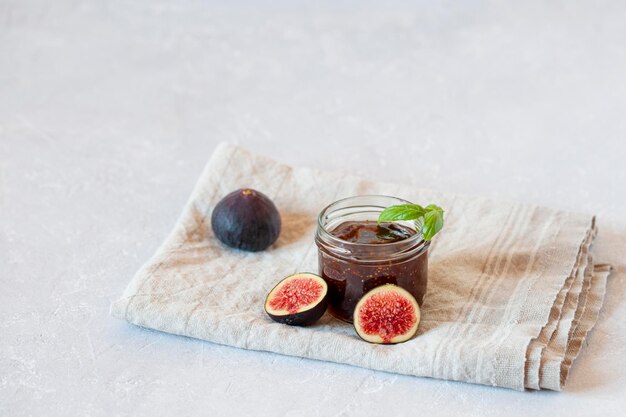 Confiture caseiro de figo orgânico em uma pequena jarra em fundo de concreto cinza vista lateral cópia espaço