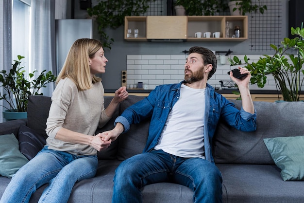 Conflicto pelea celos en el hogar familiar Pareja joven hombre y mujer La mujer está celosa toma el teléfono de su marido exige una explicación