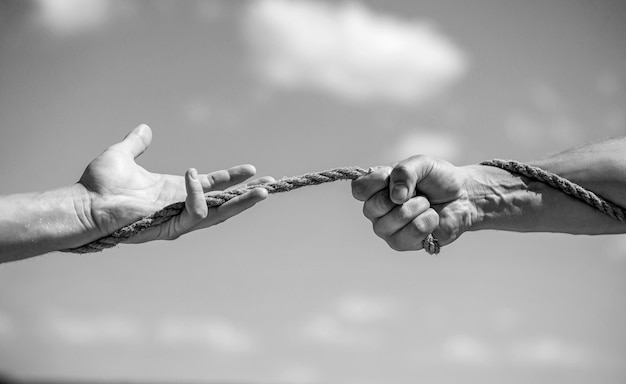 Conflito cabo de guerra Mão segurando uma corda subindo corda força e determinação Ajuda de resgate gesto de ajuda ou mãos Preto e branco