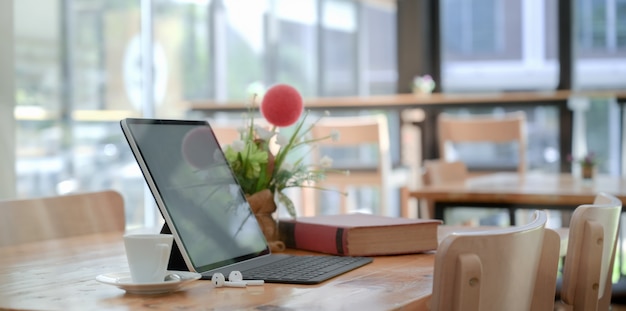 Confortável espaço de trabalho com tablet com teclado e livro, decorações e uma xícara de café