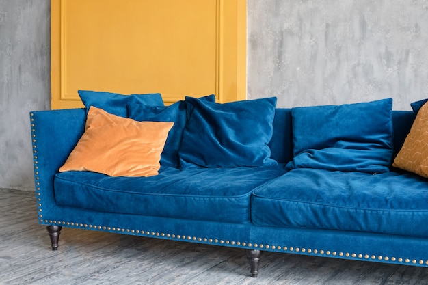 Confortável sofá azul clássico com almofadas laranja em apartamento minimalista simples
