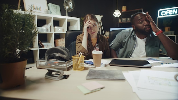 Confundido hombre afroamericano y señora hipster sintiéndose molesto en la oficina moderna