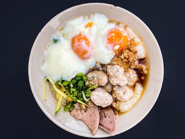 El congee de cerdo de primer plano con huevos cocidos suaves es el fondo de la comida asiática para el desayuno.