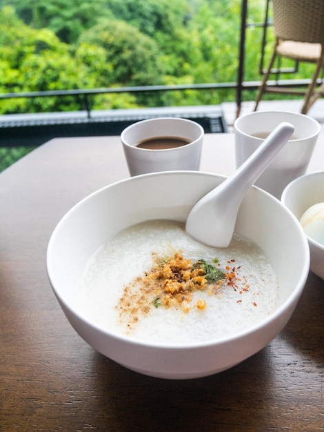 Foto congee de carne de porco picada com ovo cozido macio em tigela na mesa de madeira.