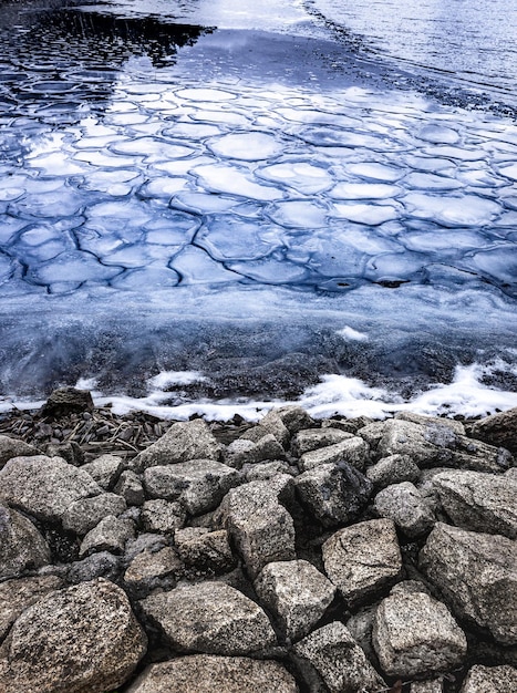 Congelando as primeiras geadas do lago em forma de pequenos cubos de gelo e grandes pedras no cenário da paisagem costeira