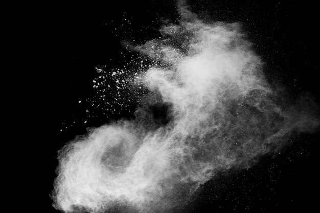 Foto congelar el movimiento de salpicaduras de partículas de polvo blanco sobre fondo negro.