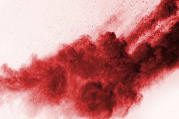 Congele o movimento do pó vermelho que explode, isolado no fundo branco.