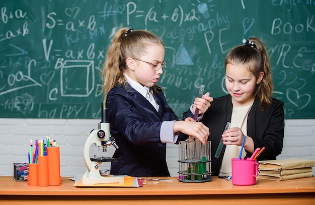 Conhecimento básico de química Alunos garotas bonitas usam tubos de ensaio com líquidos Conceito de experimento químico Medidas de segurança para fornecer reação química segura Crianças geniais trabalham em sua própria teoria química