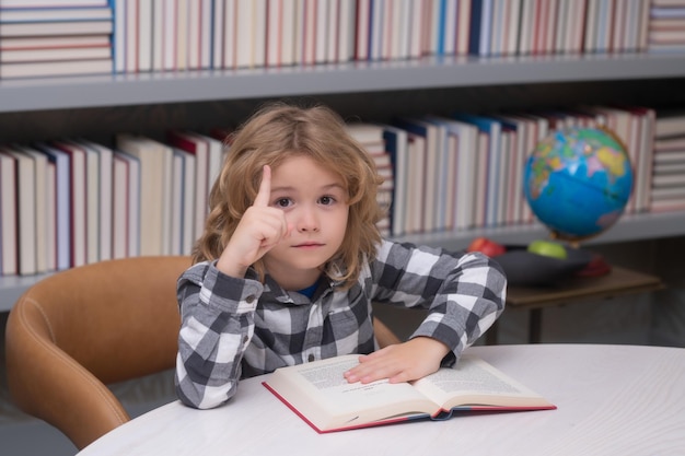 Conhecimento educacional e conceito de livraria Criança lendo um livro vermelho na biblioteca Aluno na biblioteca da escola