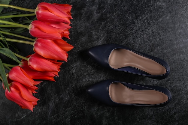 Conhecimento ou dia das mães. tulipas vermelhas com sapatos de salto alto em um quadro de giz. vista do topo.