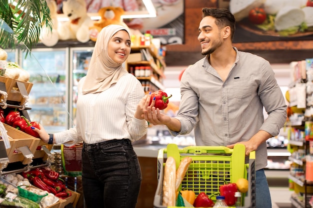 Cônjuges do Oriente Médio fazendo compras de supermercado comprando legumes no supermercado