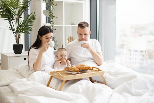 Cônjuges e filhos tomando café da manhã na cama aconchegante