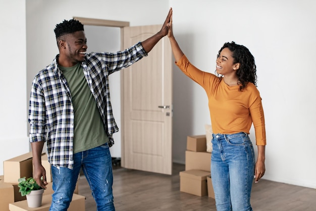 Cônjuges negros dando high five em pé entre caixas de papelão internas