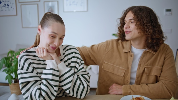 Cônjuges sorridente beijando mesa de apartamento tendo pequeno-almoço romântico em casa closeup