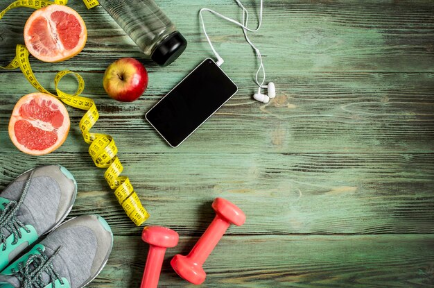 Conjunto de accesorios deportivos, agua de frutas esparcida sobre una superficie de madera de una vista superior turquesa